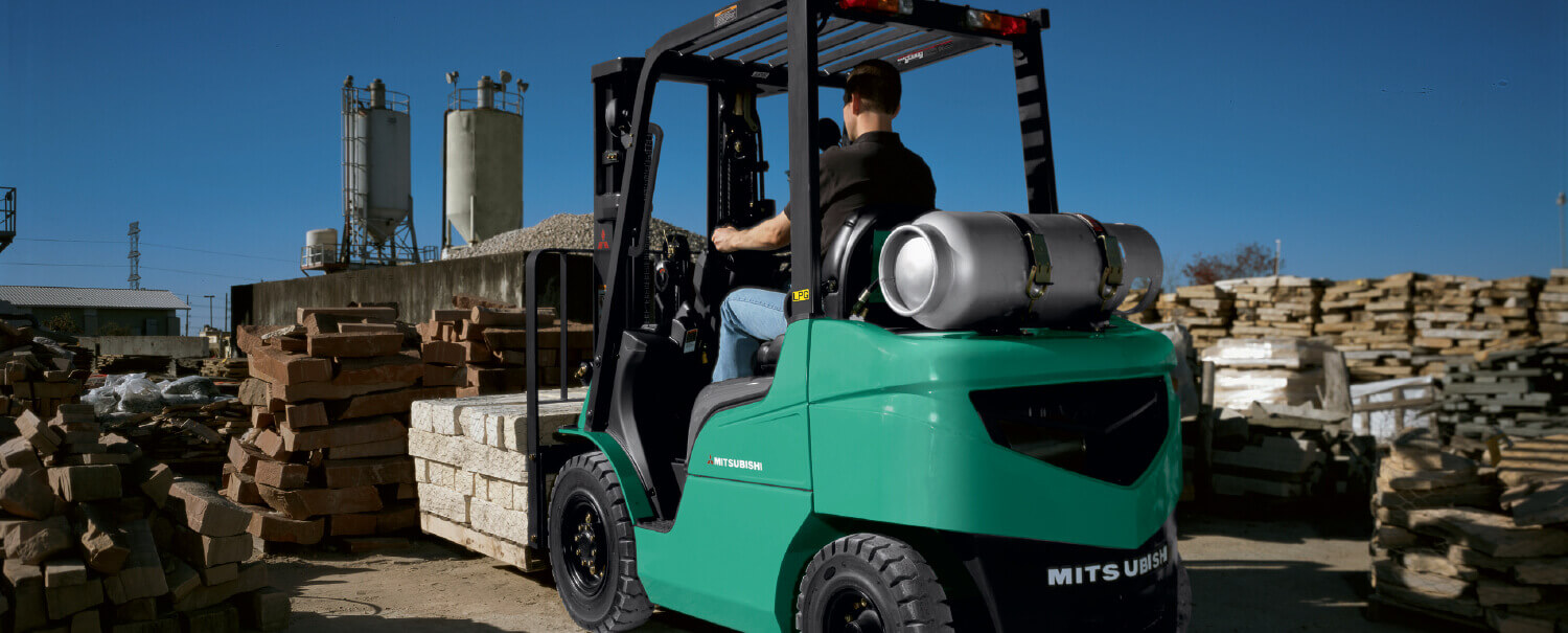 Man driving Mitsubishi IC pneumatic tire forklift away